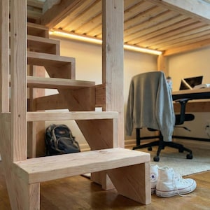 May include: A wooden staircase with a loft bed frame. The stairs are made of light-colored wood and lead up to a bed frame. A black backpack sits under the stairs. White high-top sneakers are on the floor.
