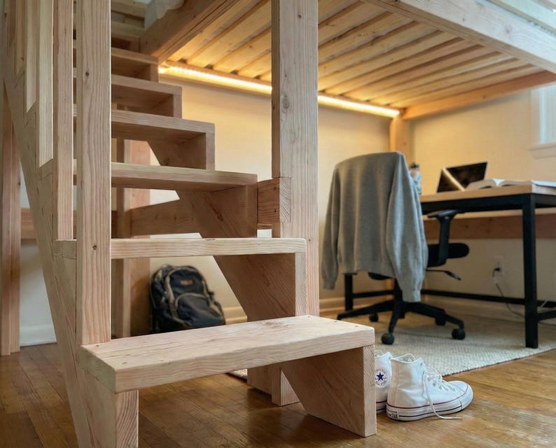 May include: A wooden staircase with a loft bed frame. The stairs are made of light-colored wood and lead up to a bed frame. A black backpack sits under the stairs. White high-top sneakers are on the floor.