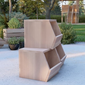May include: Three wooden storage bins stacked on top of each other. The bins are made of light wood and have a hexagonal shape. The bins are sitting on a light gray surface.