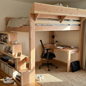 Op de afbeelding: Een lichtgekleurd houten hoogslaper met een ingebouwd bureau en een boekenplank. Het bed is verhoogd, met een bureau en stoel eronder. De boekenplank bevat opbergbakken en is geïntegreerd in de trap naar het bed.