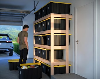 May include: A wooden storage shelf unit with multiple black storage bins with yellow lids. The shelf unit is in a garage with a white door and a car in the background.