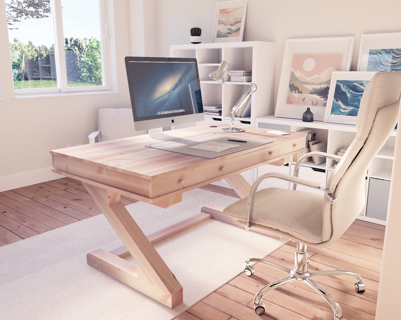 Puede incluir: Un escritorio de madera clara con una base en forma de Z y una silla de oficina blanca con un asiento de tela beige. Un monitor de computadora est&aacute; en el escritorio, junto con una l&aacute;mpara y otros suministros de oficina.