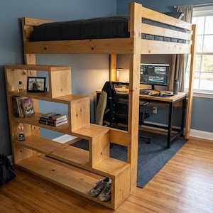 Könnte beinhalten: Ein hölzernes Hochbett mit integrierter Treppe und Regalen. Der Bettrahmen besteht aus hellem Holz und verfügt über einen Schreibtischbereich mit einem Computer. Die Treppe hat eingebaute Regale mit Büchern, einem Foto und Dekorationsartikeln. Eine dunkelgraue Matratze liegt auf dem Loft.