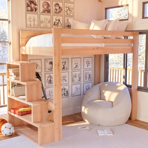 Puede incluir: Una cama litera de madera con una escalera y estantes incorporados. La cama tiene un colch&oacute;n blanco y un puf blanco se encuentra delante de ella. La pared detr&aacute;s de la cama est&aacute; decorada con dibujos en blanco y negro.