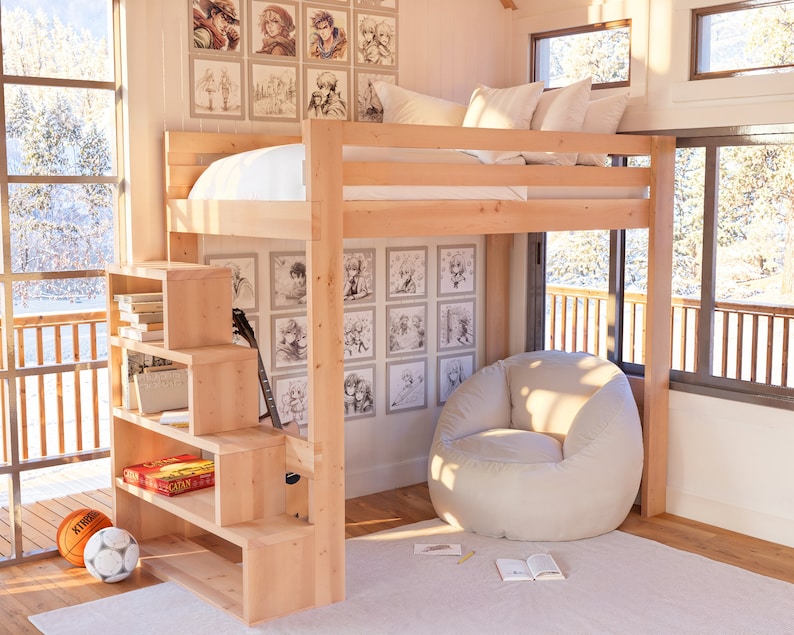 Puede incluir: Una cama litera de madera con una escalera y estantes incorporados. La cama tiene un colch&oacute;n blanco y un puf blanco se encuentra delante de ella. La pared detr&aacute;s de la cama est&aacute; decorada con dibujos en blanco y negro.