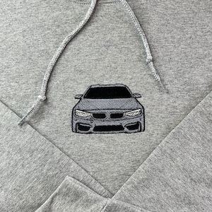 May include: A gray hooded sweatshirt with a black embroidered car on the front.