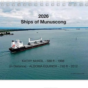 Może przedstawiać: Kalendarz "2026 Ships of Munuscong" z frachtowcem na wodzie. Tekst zawiera "KATHY MCKEIL - 179.2 m - 1998" i "ALGOMA EQUINOX - 225.6 m - 2012". Tło przedstawia zachmurzone niebo i odległą linię brzegową.