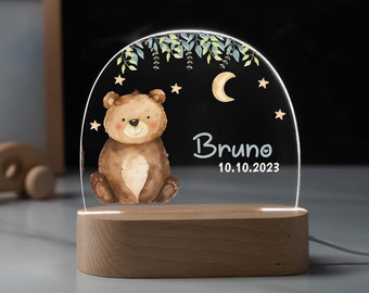 Puede incluir: Una luz nocturna de madera con un inserto de acrílico transparente que presenta un oso de dibujos animados, una luna creciente y estrellas. El texto "Bruno 10.10.2023" está impreso en el inserto de acrílico.