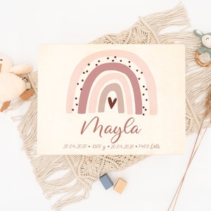May include: A wooden sign with a pink and brown rainbow with white polka dots and a small heart in the center. The name "Mayla" is written in cursive below the rainbow. The date "20.04.2020" and the weight "3500 g" are written below the name. The date "20.04.2020" and the time "14:03 Uhr" are written below the weight.