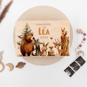 Pode incluir: Caixa de madeira para memórias com um design de animais da floresta. A caixa é decorada com um urso, um lobo, um coelho, um veado, um esquilo e uma abelha. O texto na caixa diz "Erinnerungskiste von LEA 20.09.2022".