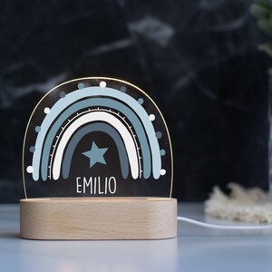 May include: A blue and white rainbow night light with a star and the name "EMILIO" on a wooden base.