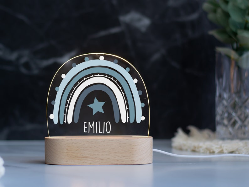 May include: A blue and white rainbow night light with a star and the name "EMILIO" on a wooden base.