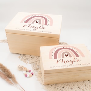 May include: Two wooden keepsake boxes with rainbow designs and the name "Mayla" and birth date information. The boxes are stacked on top of each other.
