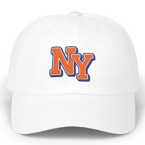 Könnte beinhalten: Eine weiße Baseballkappe mit den Buchstaben NY, die in Orange mit einer dunkelblauen Umrandung auf der Vorderseite aufgestickt sind. Die Kappe hat eine strukturierte Krone, einen gebogenen Schirm und einen Knopf oben, schlichtes Design.