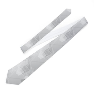 Può includere: Una cravatta grigio chiaro con un motivo geometrico. La cravatta è realizzata in un tessuto liscio e presenta un motivo ripetuto di forme sovrapposte in tonalità di grigio e bianco. La cravatta è angolata su uno sfondo bianco.