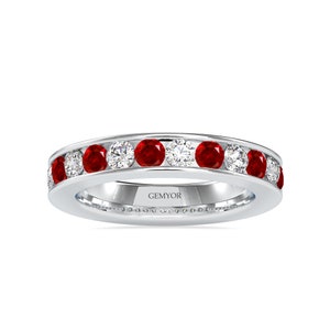 Op de afbeelding: Een zilveren bandring met een rij van afwisselende rode robijnen en witte diamanten. De ring is gegraveerd met het woord "GEMYOR".