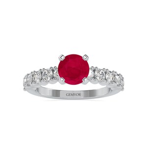 Pode incluir: Um anel de prata com uma gema de rubi vermelho e uma banda de pequenos diamantes.