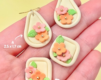May include: A pair of handmade polymer clay earrings with floral designs. The earrings are in the shape of a teardrop and a square. The teardrop earrings are 2.5 inches by 1.7 inches and the square earrings are 1.7 inches. The earrings are white with pink and orange flowers and green leaves.