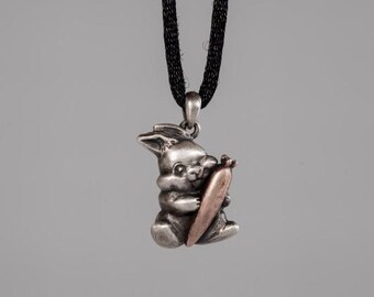 May include: Silver pendant necklace featuring a rabbit holding a carrot. The rabbit is silver and the carrot is copper.