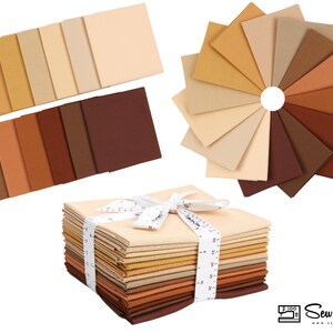 May include: A stack of 20 fat quarter fabric squares in various shades of brown, beige, and cream. The fabric is arranged in a color gradient from light to dark. The fabric is tied with a white ribbon and a measuring tape.