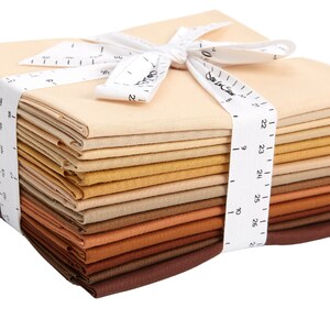 May include: A stack of 20 beige, brown, and tan fabric squares tied together with a white ribbon. The ribbon has a white measuring tape printed on it.