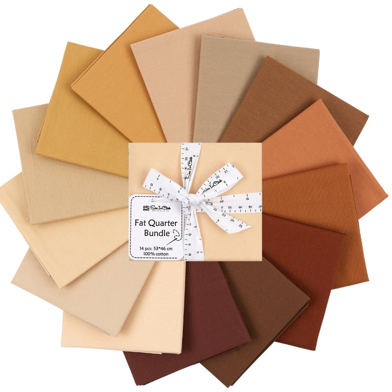 May include: A bundle of 14 fat quarter fabric squares in shades of brown, beige, and tan. The fabric squares are arranged in a circle with a white ribbon tied around the center. The label reads "Fat Quarter Bundle, 14 pcs: 53x46 cm, 100% cotton."