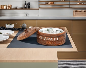 Puede incluir: Un recipiente de madera con un diseño tallado intrincado y un cuenco interior de acero inoxidable. El recipiente está etiquetado como "CHAPATI" y tiene una tapa que está parcialmente abierta. El recipiente está sentado sobre una superficie de madera.
