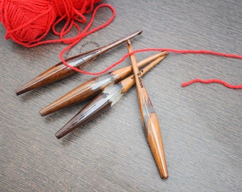May include: Four wooden knitting needles with a red ball of yarn. The needles are 6.5 mm and 8 mm in size.