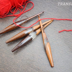 K&ouml;nnte beinhalten: Drei Stricknadeln aus Holz mit rotem Garn. Die Nadeln sind 3,5 mm, 4,0 mm und 6,5 mm.