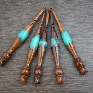 May include: Set of five wooden crochet hooks with turquoise resin handles. The hooks are labeled with sizes 5.5mm, 6.0mm, 6.5mm, 7.5mm, and 9.0mm.