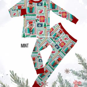 May include: A mint green pajama set with a festive Christmas theme. The long-sleeved top and pants feature a repeating pattern of nutcrackers, gifts, and Christmas trees. The cuffs and neckline are red, and the word "MINT" is printed on the set.