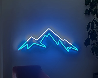 May include: A wall-mounted neon sign depicting a stylised mountain range. The design features a bright blue light outline that forms the peaks and slopes of the mountains, creating a glowing effect against the wall surface.