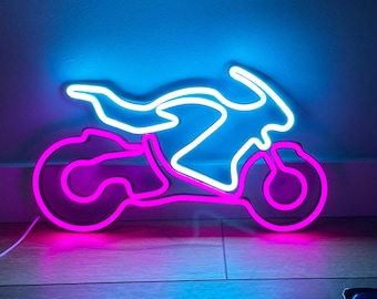 Może przedstawiać: Neonowy szyld w kształcie motocykla z jasnoniebieską górną częścią i żywą różową dolną częścią. Szyld emituje świecące światło, tworząc wyraźną sylwetkę motocykla sportowego. Obok znajduje się ciemna butelka perfum oraz okulary przeciwsłoneczne.