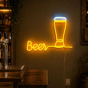 May include: A neon sign mounted on a wall featuring the word Beer in a cursive yellow font, connected to a stylized outline of a beer glass with a yellow body and a white foam top. A thin power cord hangs down from the bottom of the sign.