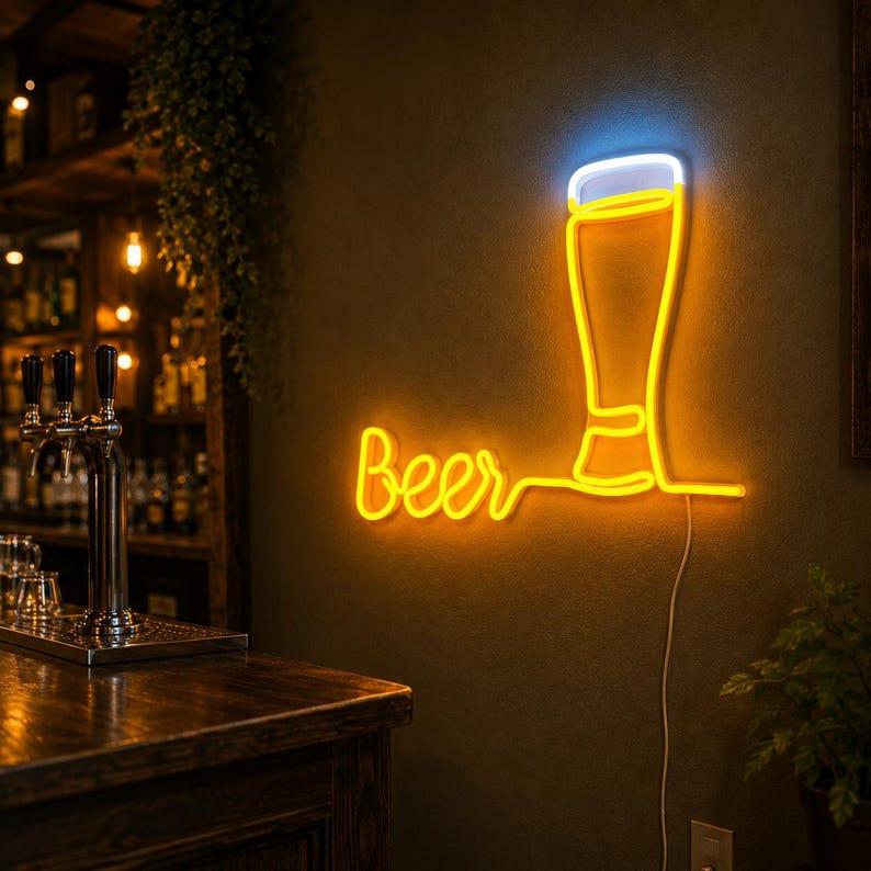 May include: A wall-mounted neon sign featuring the word Beer in a cursive yellow font next to a stylized outline of a beer glass with a yellow body and a white foam top. The sign is illuminated against a dark wall with a visible power cord.