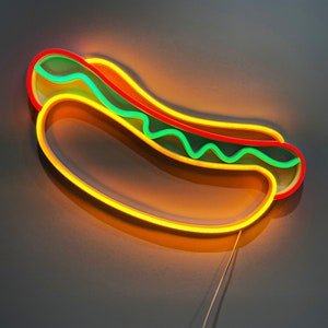 May include: A neon sign shaped like a hot dog with yellow, red, and green neon lights.