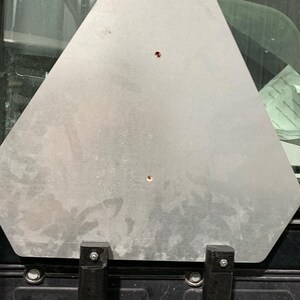 May include: A silver metal triangle shaped sign with two black metal brackets attached to the bottom.