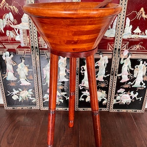 Könnte beinhalten: Eine große Salatschüssel aus Holz mit einem Ständer. Die Schüssel ist aus dunklem Holz und hat eine natürliche Oberfläche. Der Ständer ist aus dem gleichen Holz und hat drei Beine.