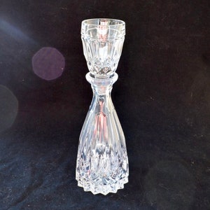 May include: A clear glass decanter with a stopper. The decanter has a textured, faceted design.