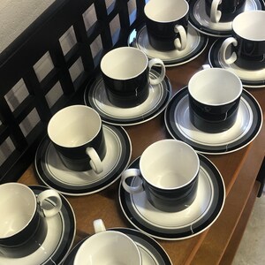 Puede incluir: Un juego de tazas y platillos de cerámica en blanco y negro. Las tazas tienen forma cilíndrica con interior blanco y exterior negro. Los platillos presentan círculos concéntricos negros, grises y blancos.