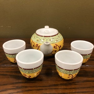 Peut inclure: Une théière jaune et verte avec un motif floral et quatre tasses à thé assorties.