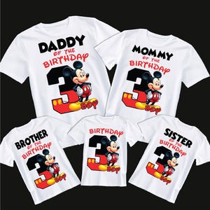 May include: White t-shirts with Mickey Mouse graphics. Each shirt features a different text: "Daddy of the Birthday", "Mommy of the Birthday", "Brother of the Birthday", "Birthday", and "Sister of the Birthday". The number "3" is prominent.