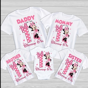 May include: White t-shirts and a babygrow featuring a Minnie Mouse design. Each top has a pink number 1, a bow, and the words "Daddy", "Mommy", "Brother", and "Sister" above the Minnie Mouse graphic. The babygrow has the same design.