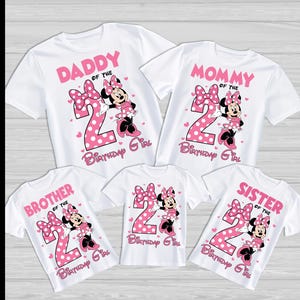 Może przedstawiać: Białe koszulki z r&oacute;żowymi grafikami Myszki Minnie, dużą cyfrą 2 oraz napisami "Daddy", "Mommy", "Brother", "Sister" i "Birthday Girl". Idealne na rodzinną uroczystość.