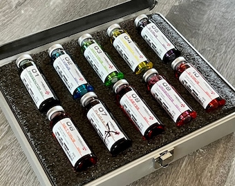Peut inclure: Une mallette argentée ouverte contenant dix fioles remplies de liquides colorés. Chaque fiole est numérotée et étiquetée avec des termes tels que "PROGENITOR", "T-VIRUS" et "G-VIRUS". Les fioles sont disposées dans un insert en mousse gris foncé.