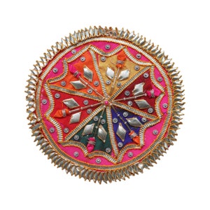 May include: A circular, multi-colored fabric mandala with a silver and gold border. The mandala is made of different colored fabrics and has a beaded center.