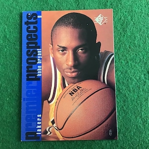 Puede incluir: Una tarjeta de intercambio con un jugador de baloncesto que lleva una camiseta púrpura y dorada, sosteniendo un balón de baloncesto. La tarjeta tiene el texto "Prospects" y "Kobe Bryant" en el lado izquierdo y "SP" en el lado derecho.