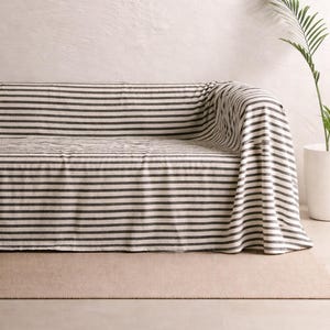 Puede incluir: Una taza de cerámica blanca con asa negra y el texto "But First, Coffee" en negrita negra. La taza se encuentra sobre un fondo neutro, resaltando su diseño sencillo.