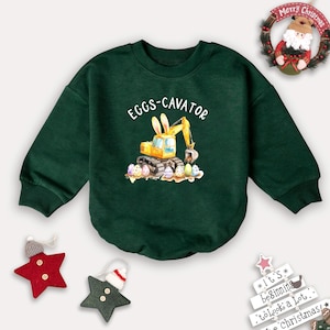 May include: Green long-sleeved sweatshirt with a yellow excavator cartoon and the text "EGGS-CAVATOR".