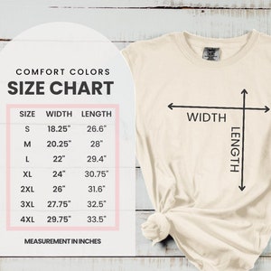 May include: Cream-coloured t-shirt with a size chart graphic. The chart displays measurements in inches for sizes S through 4XL, including width and length. The shirt has a crew neck and a knotted hem.